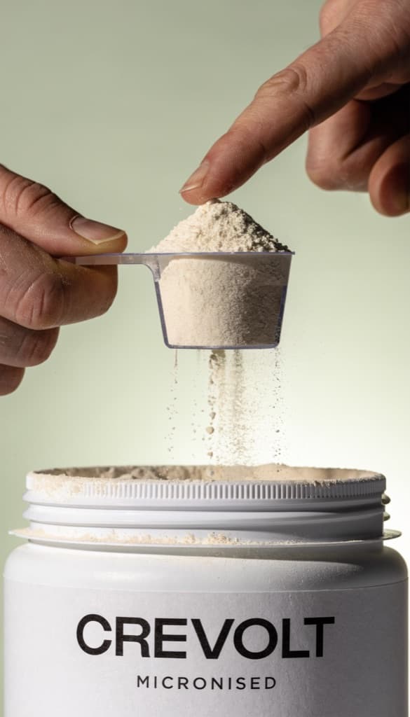 Fingers levelling a full scoop over the open product